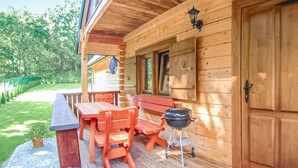 A wooden cabin with a covered porch, a barbecue grill, and a table with chairs. - Gorgeous home in Jaroslawiec with WiFi (Jaroslawiec)