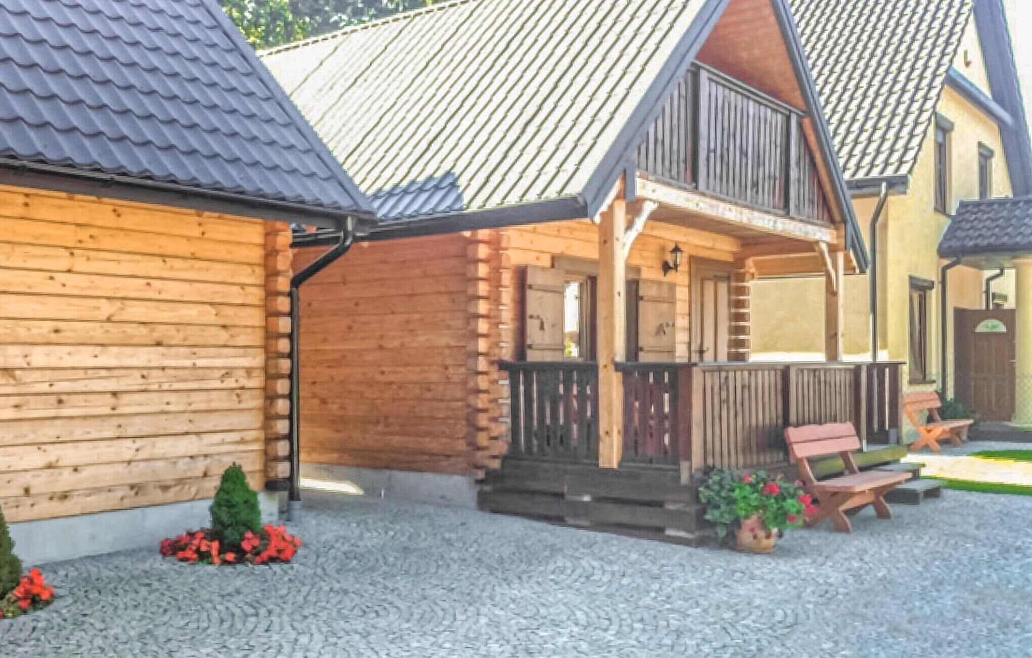 A wooden house with a balcony, a wooden fence, and a gravel driveway.