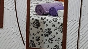Ett sovrum med en säng, en spegel och ett blommigt sängöverkast.
