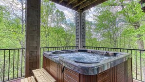 Un bain à remous sur une terrasse en bois, avec vue sur une forêt.