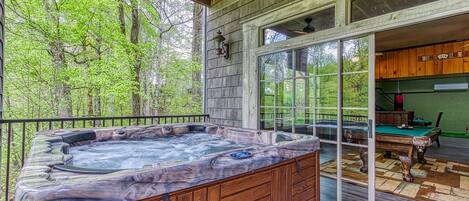 A wooden deck with a hot tub, a pool table, and a billiards table.