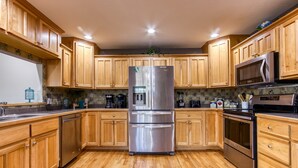 Une cuisine moderne avec des meubles en bois, des appareils électroménagers en acier inoxydable et un dosseret carrelé.