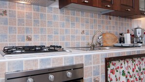 A kitchen with a gas stove, stainless steel oven, and a tiled backsplash. - Beautiful 1-bed House in Avola (Avola)