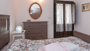 A bedroom with a bed, a dresser, a mirror, and a door with curtains. - Beautiful 1-bed House in Avola (Avola)