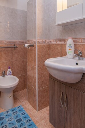 A bathroom with a bidet, a sink, and a bottle of Johnson's body care.