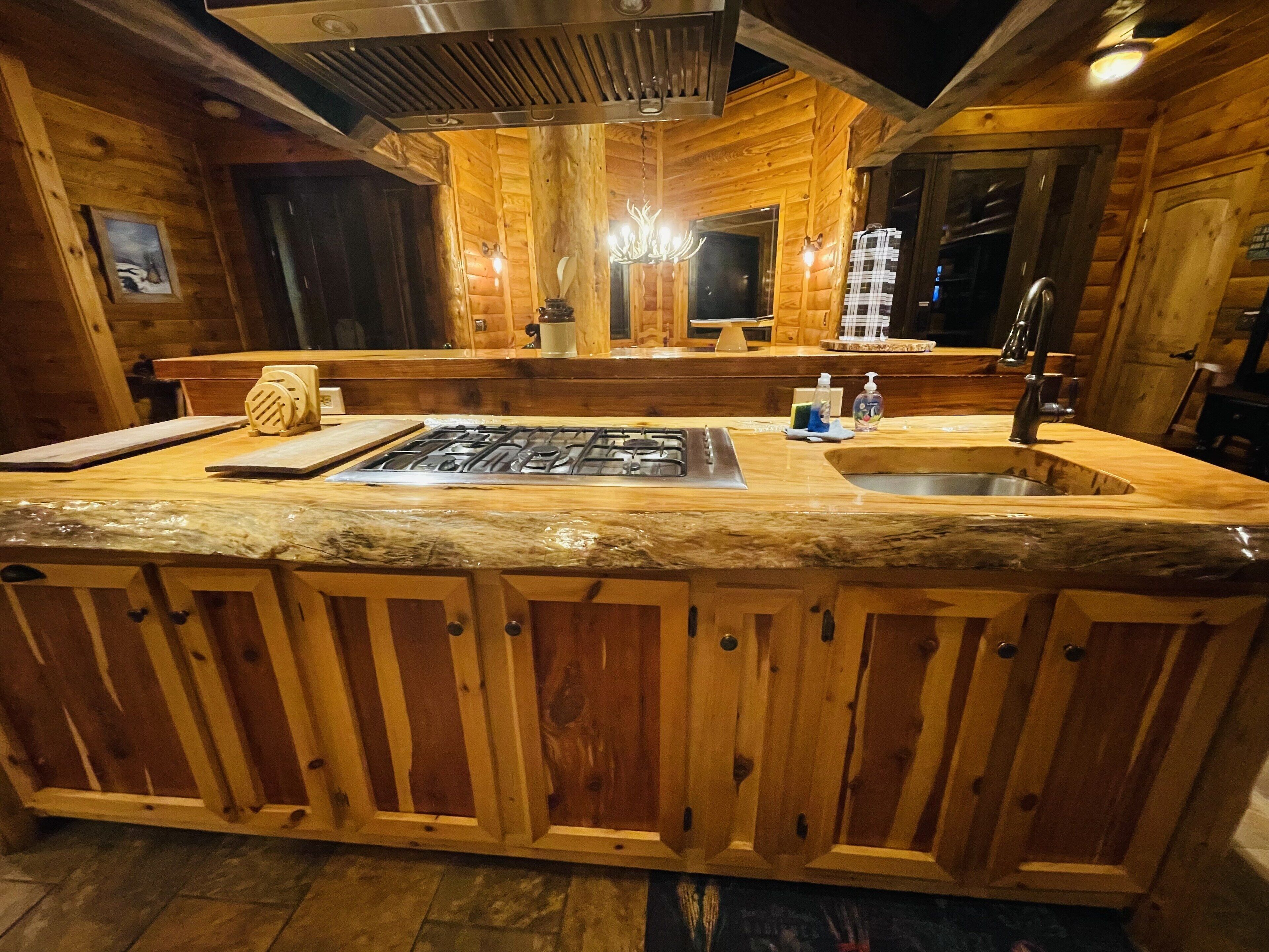 Een houten cabinestinterieur met een keukenhoek, voorzien van een marmeren aanrecht, een spoelbak en een fornuis.
