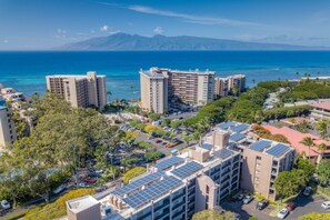 A high-rise hotel with multiple floors, solar panels on the roof, and a view of the ocean.