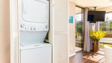 Une buanderie équipée d’un lave-linge et d’un sèche-linge à chargement frontal, d’un téléviseur fixé au mur et d’une fenêtre donnant sur l’extérieur.