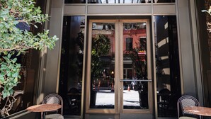A hotel entrance with a glass door, a black and green doormat with a large 'R', and two wicker chairs outside. - Root Karaköy Bosphorus Hotel & Spa (Istanbul)
