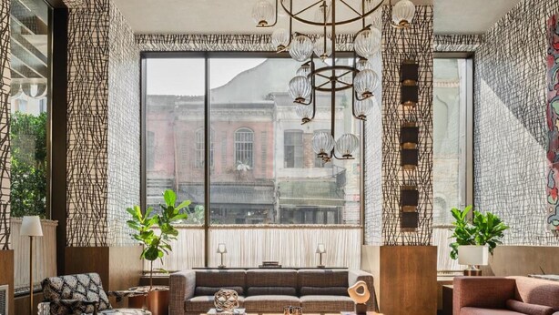 A modern living room with a large window, a sofa, a coffee table, and decorative plants. - Root Karaköy Bosphorus Hotel & Spa (Istanbul)