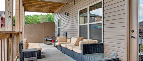Un área de patio techada con un conjunto de sofás, una mesita y una silla.