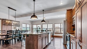 Una cocina amplia con armarios de madera, una isla central e iluminación colgante.
