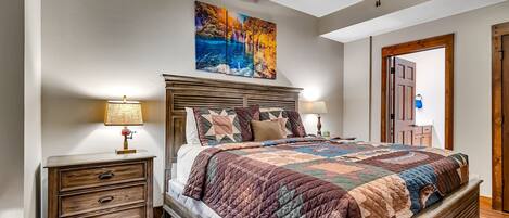 Un dormitorio con una cama de madera, una mesita de noche, una lámpara y un cuadro en la pared.