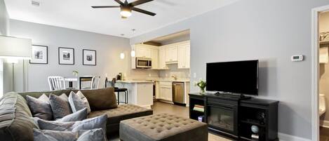 A modern living room with a sofa, ottoman, and a flat-screen TV.