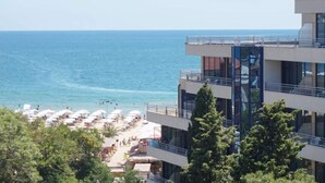 A beachfront hotel with multiple balconies overlooking the sea, a pool area with umbrellas, and a clear view of the ocean. - Hotel Royal Beach 5 Premium - Central Sea View G6 (Sunny Beach)