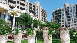 A hotel with multiple floors, balconies, and a well-maintained garden with potted plants and flowers. - Hotel Royal Beach 5 Premium - Central Sea View G6 (Sunny Beach)