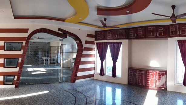 A spacious room with a curved ceiling, two ceiling fans, and a large window with curtains. - Hotel Blue Stone (Puducherry)