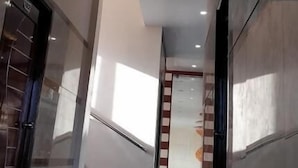 A corridor with a modern ceiling design featuring geometric patterns and recessed lighting. - Hotel Blue Stone (Puducherry)