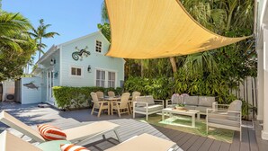 Une terrasse extérieure couverte, aménagée avec une table et des chaises, un canapé et un hamac.
