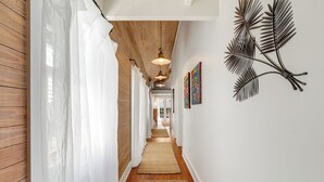 Un couloir aux murs lambrés, aux murs blancs et agrémenté d’une œuvre décorative en métal représentant des feuilles.