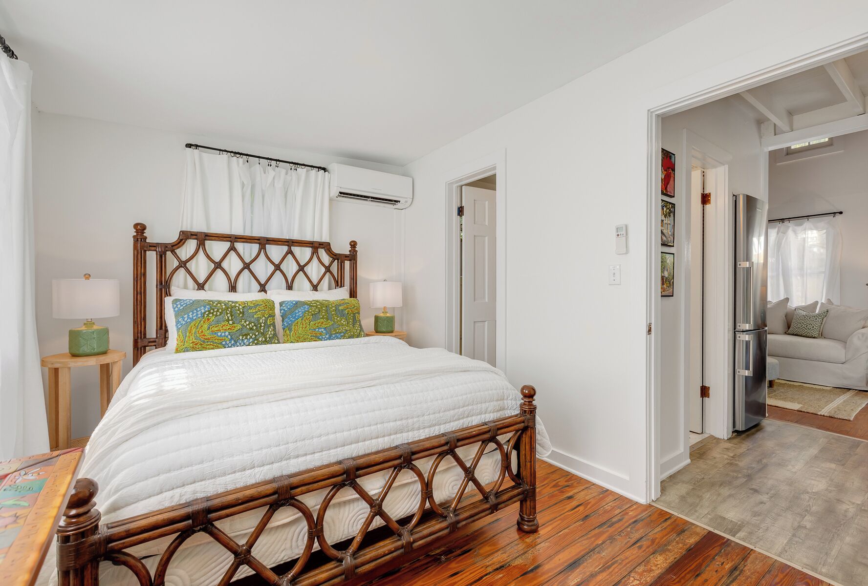 A bedroom with a wooden bed, white walls, a wooden floor, and a white ceiling.