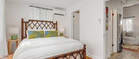 A bedroom with a wooden bed, white walls, a wooden floor, and a white ceiling.
