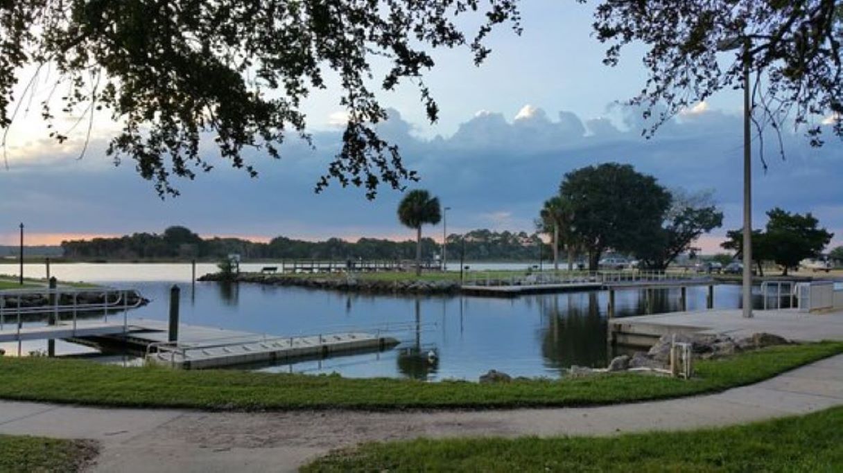 A calm lake with a dock and grassy areas.
