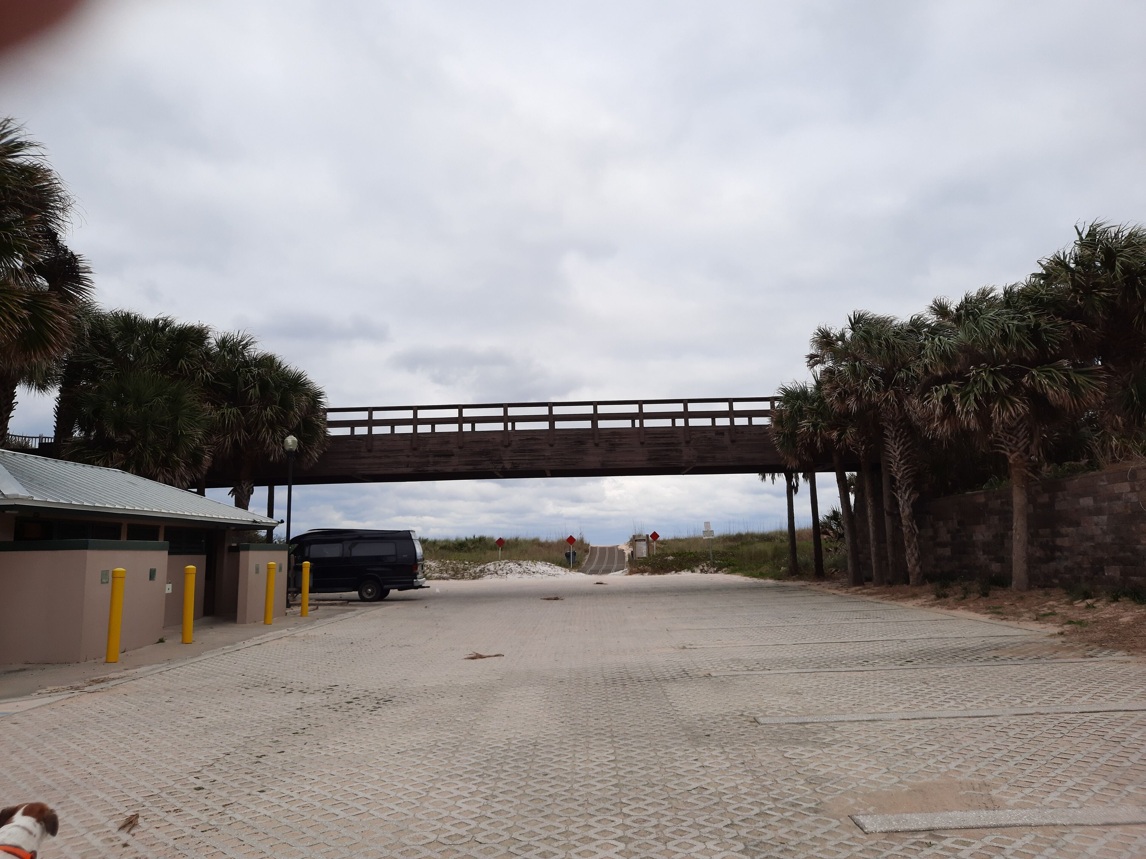 A paved pathway under a bridge with a vehicle parked on the side.