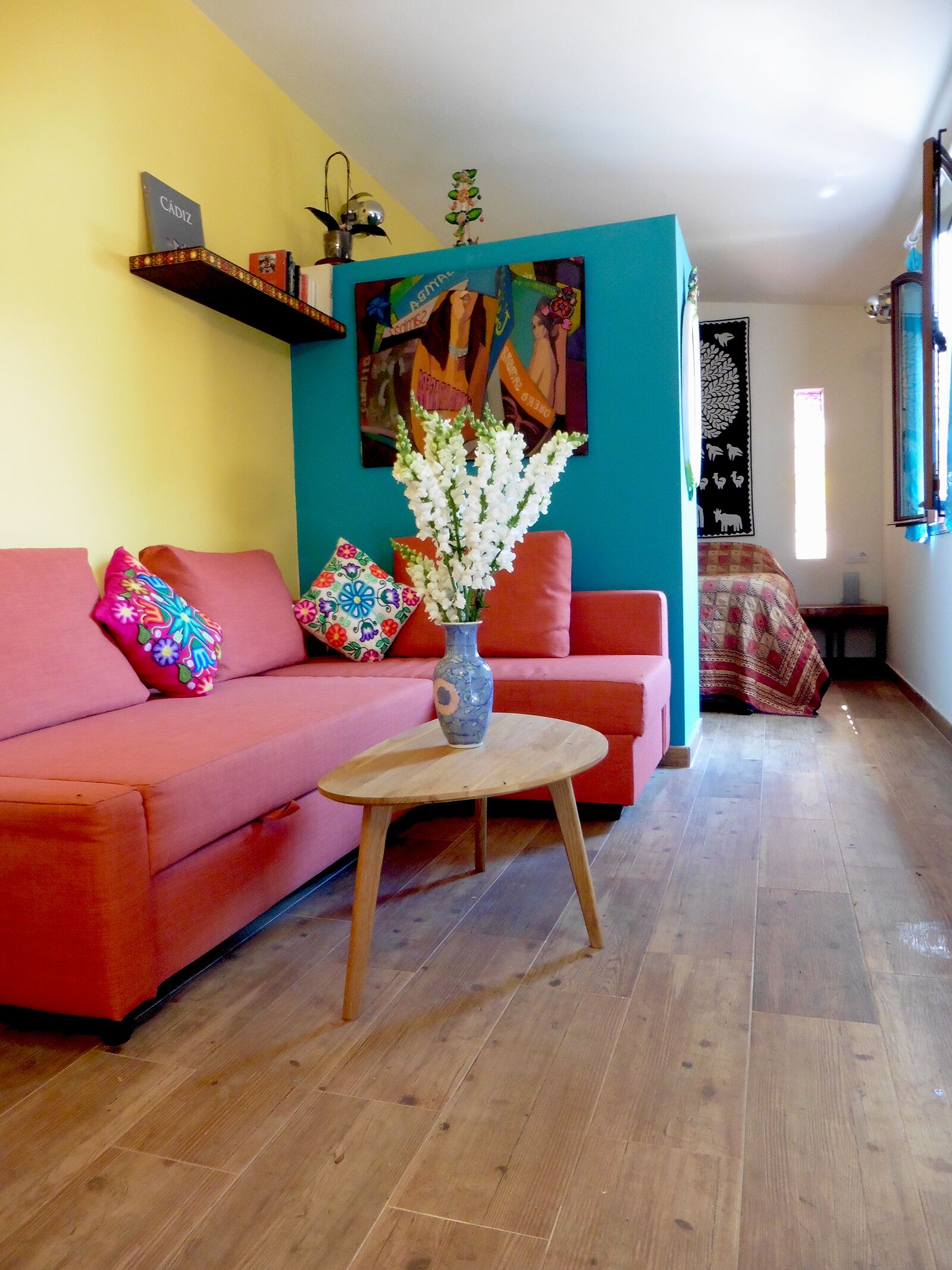 Una sala de estar con un sofá rojo, una mesa de centro de madera y un jarrón con flores.
