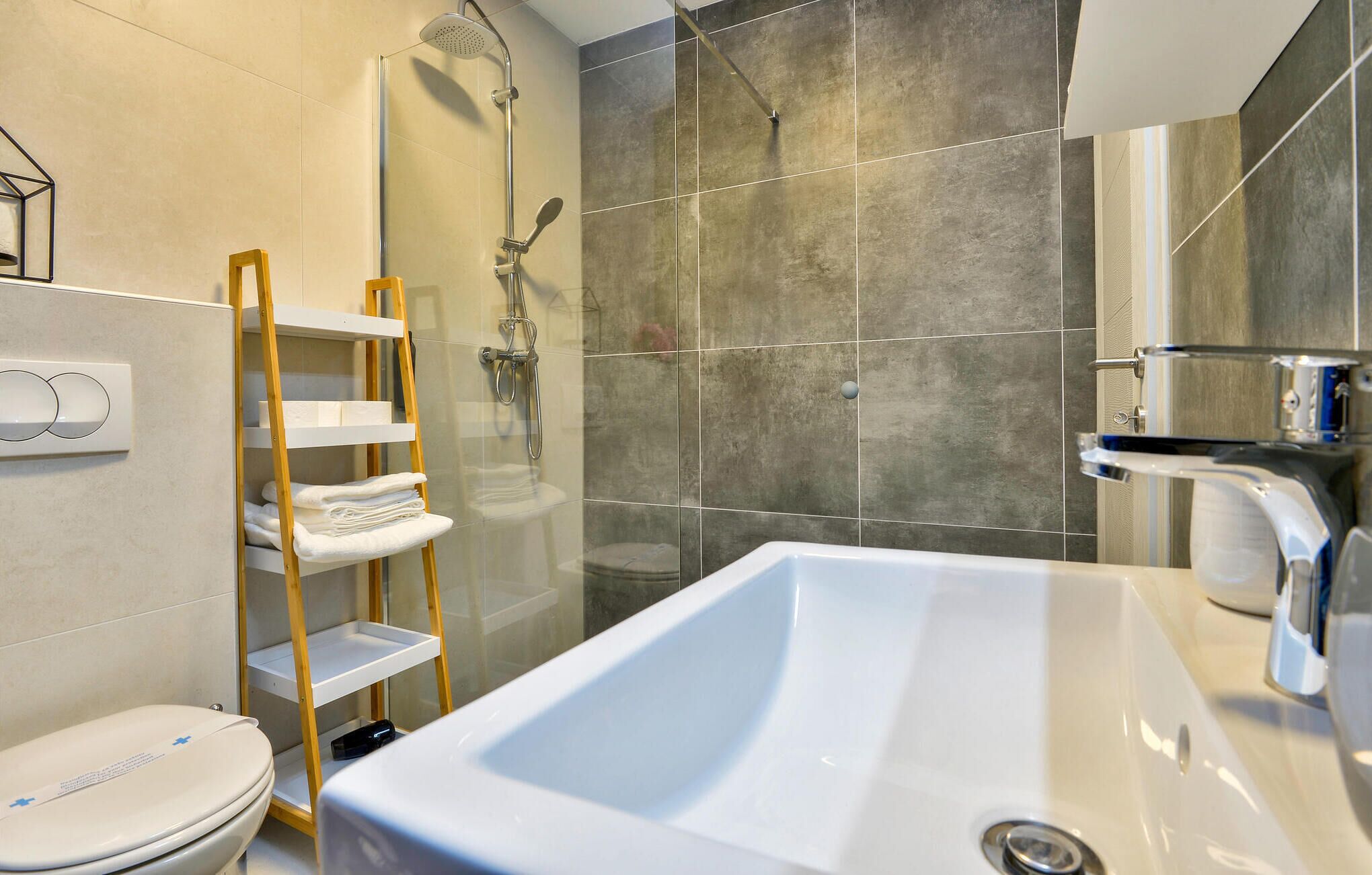 Un baño moderno con ducha de vidrio, lavamanos blanco y retrete.