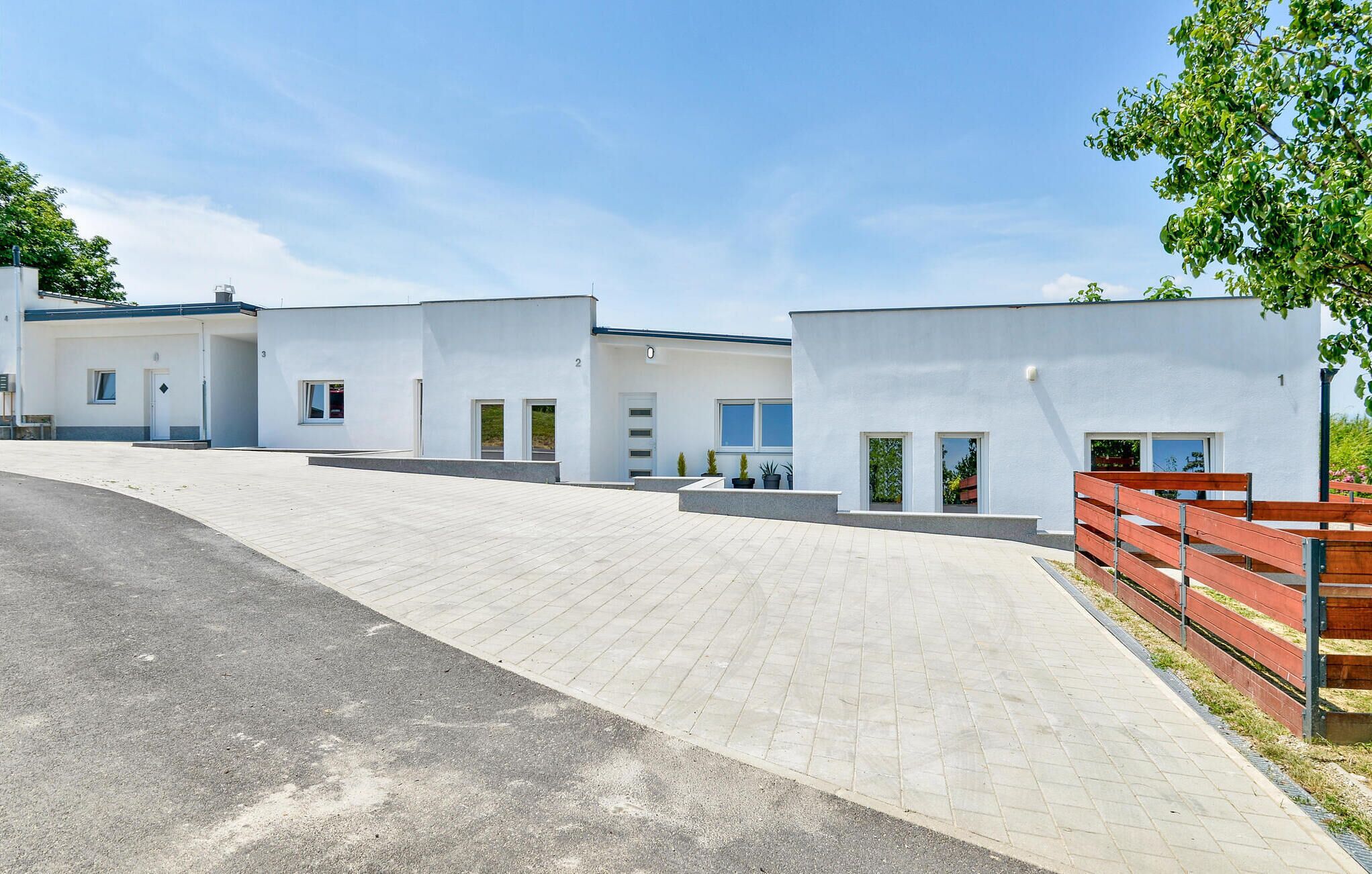 A modern building with three units, each featuring a door and windows.