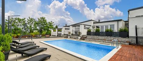 Een buitenzwembad, ligstoelen bij het zwembad