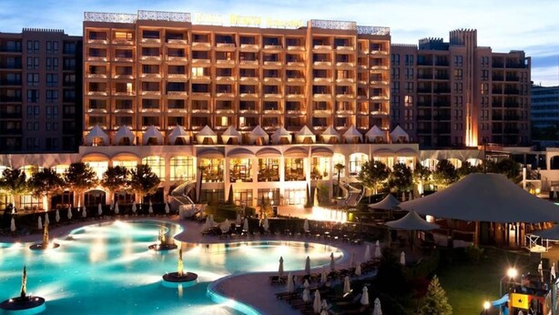 A hotel with multiple floors, a swimming pool, and outdoor seating areas.