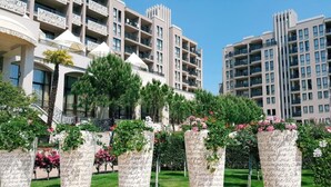 A hotel with multiple floors, balconies, and a well-maintained garden with potted plants and flowers.