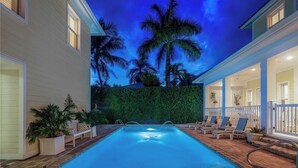 A swimming pool with a brick deck, lounge chairs, and palm trees in the background. - NEAPOLITAN SKY - Key West Style Home in Olde Naples (Naples)