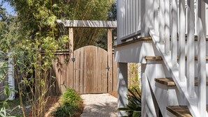 A wooden gate leading to a white building with a staircase. - Modern coastal retreat steps from Center Street and the beach (Folly Beach)