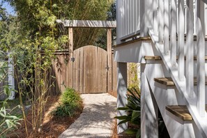 A wooden gate leading to a white building with a staircase.