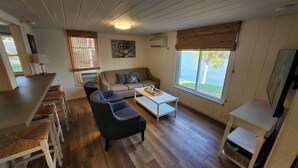 A cozy living room with a sofa, chairs, a coffee table, and a TV. - Wet Feet Retreat! Lake front cabin in quiet cove. (Caddo)