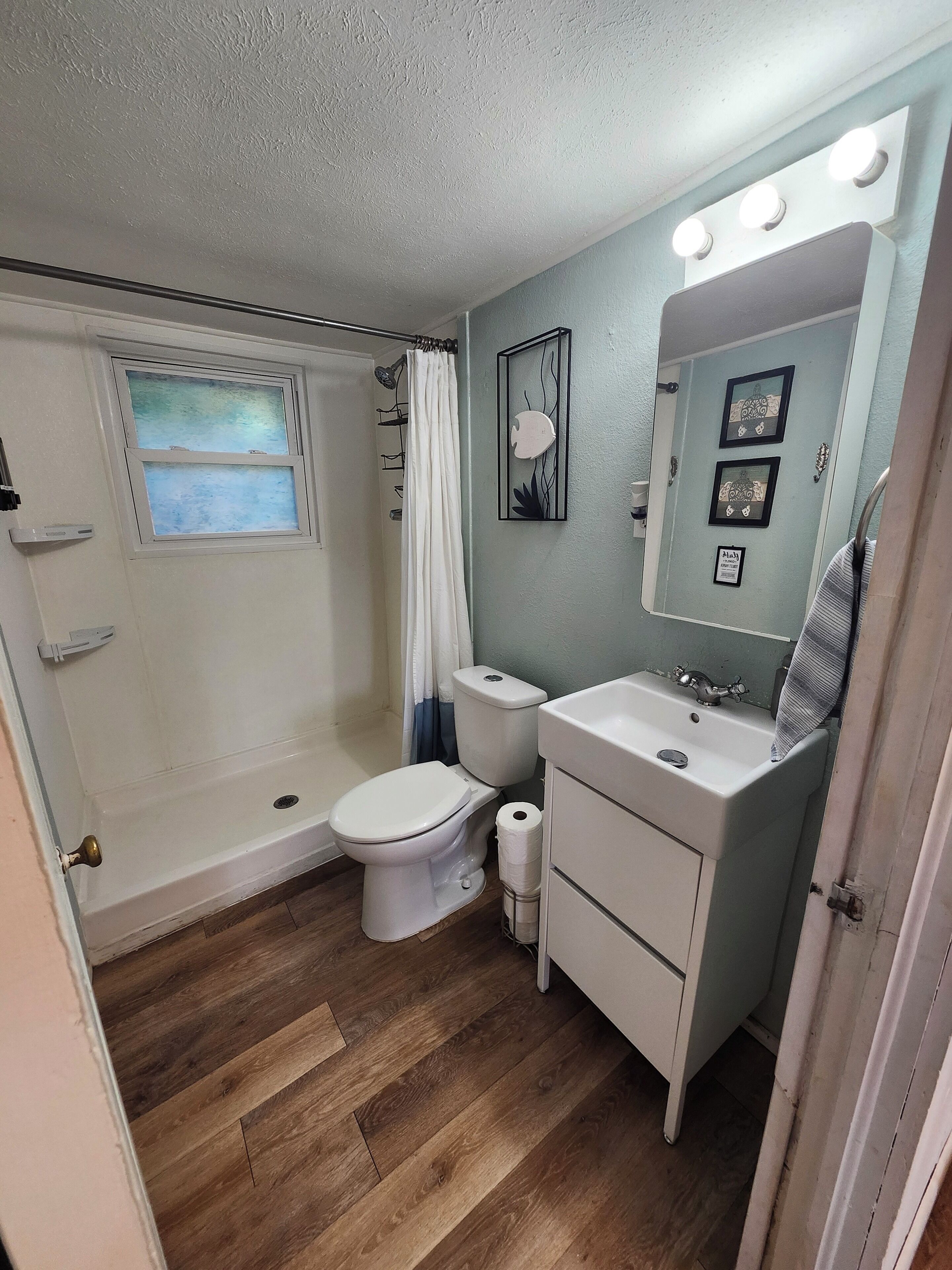A bathroom with a shower, toilet, sink, and vanity.