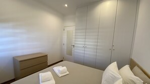 A bedroom with a bed, two towels, a dresser, and a wardrobe. - Tossan House in Vilamoura Downtown (Quarteira)
