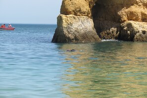 A coastal scene with a large rock formation and calm sea.