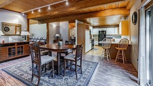 A spacious dining area with a wooden table and chairs, a kitchen in the background, and a large mirror on the wall. - Wildlife Retreat in the Forest (Becket)