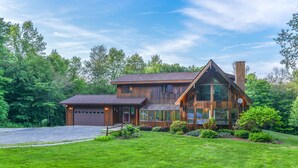 A two-story wooden house with a garage, large windows, and a well-maintained lawn. - Wildlife Retreat in the Forest (Becket)