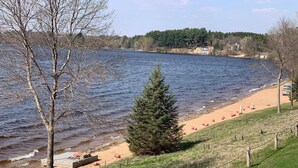 En vacker utsikt över sjön med en sandstrand, ett trästaket och en rad strandstolar och parasoller.