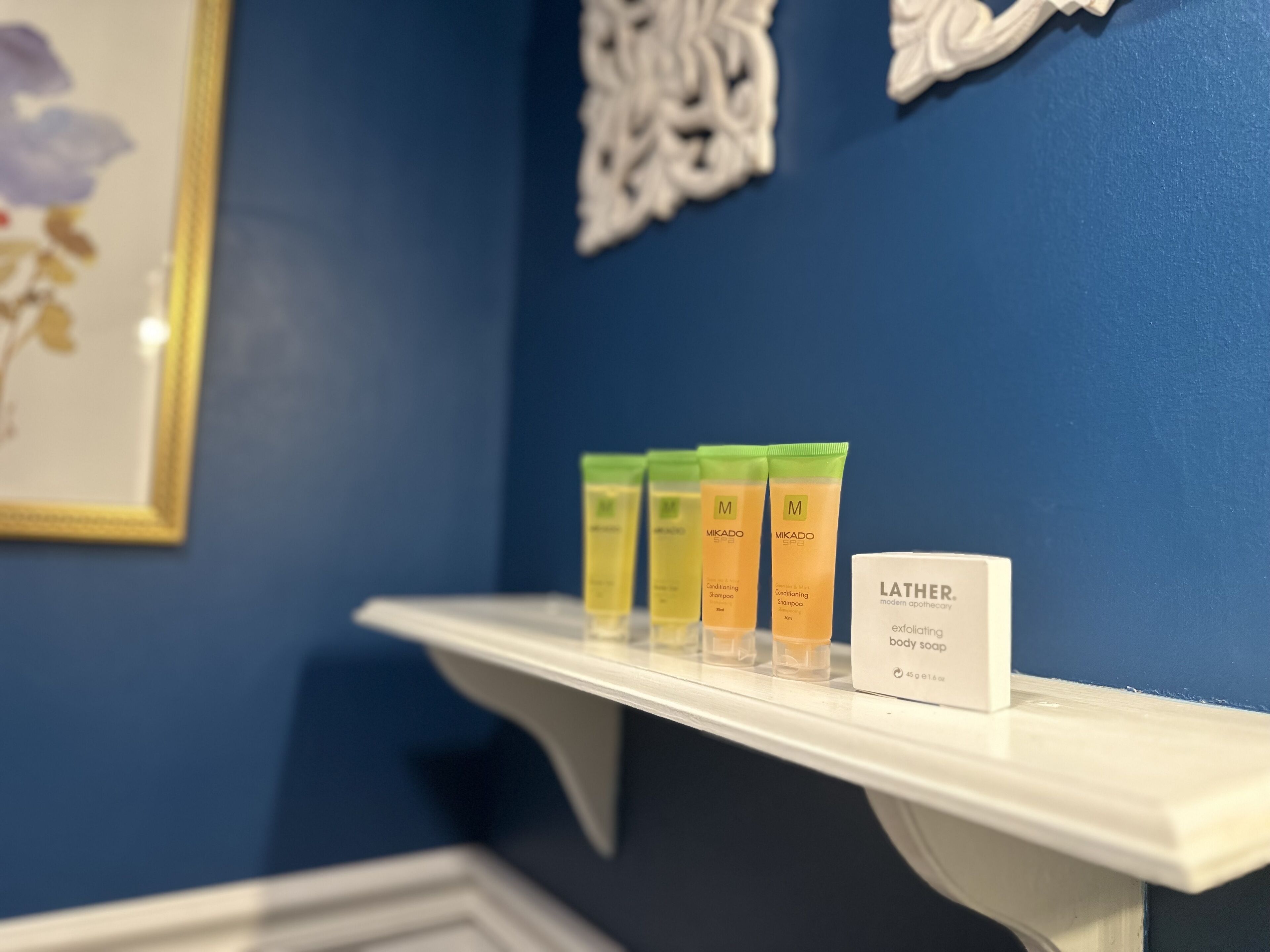 A shelf with three bottles of Mikado body soap and a Lather body soap.