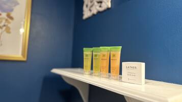 A shelf with three bottles of Mikado body soap and a Lather body soap.