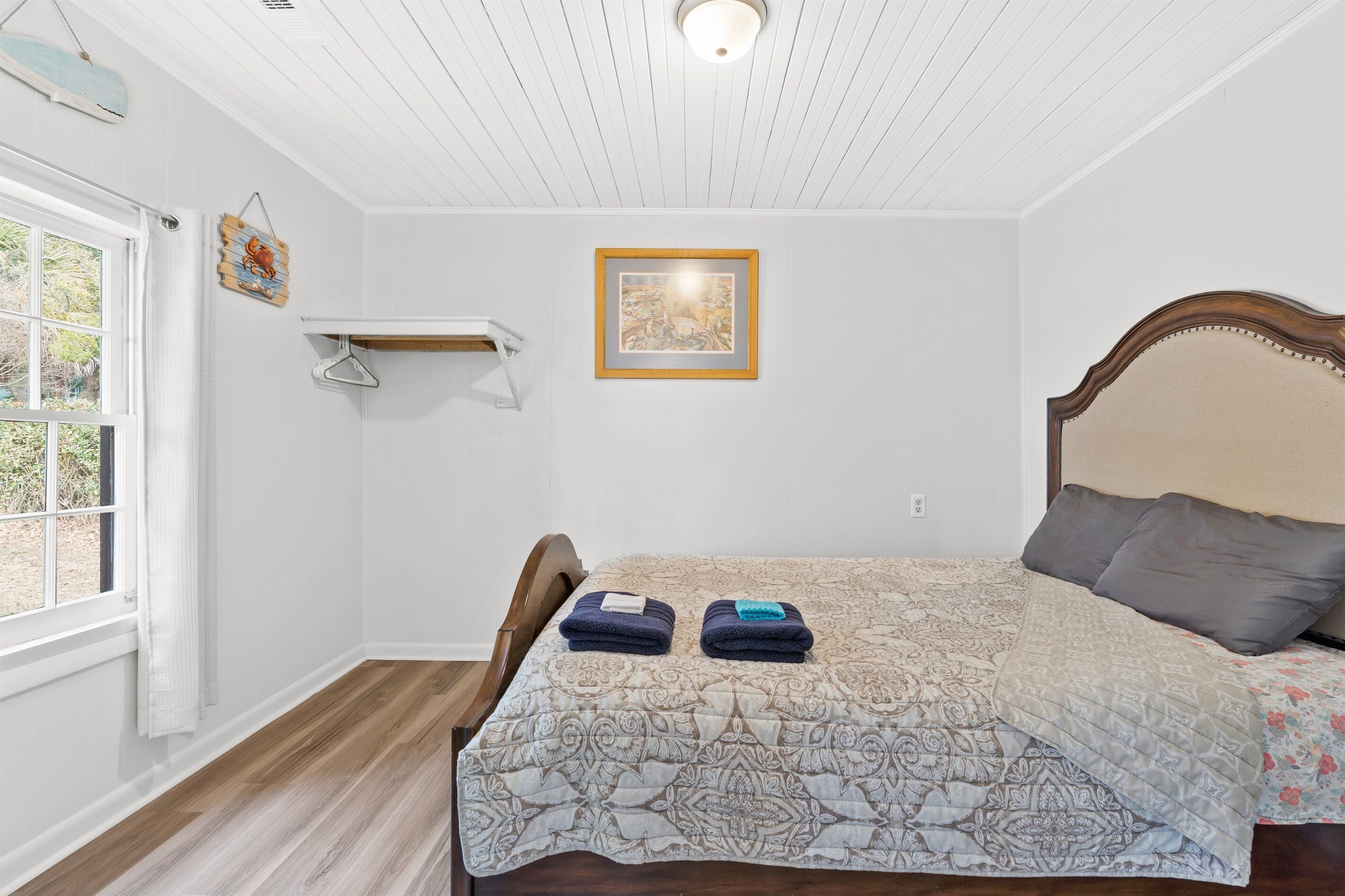 Un dormitorio con cama, lámpara colgante, ventana y estante en la pared.