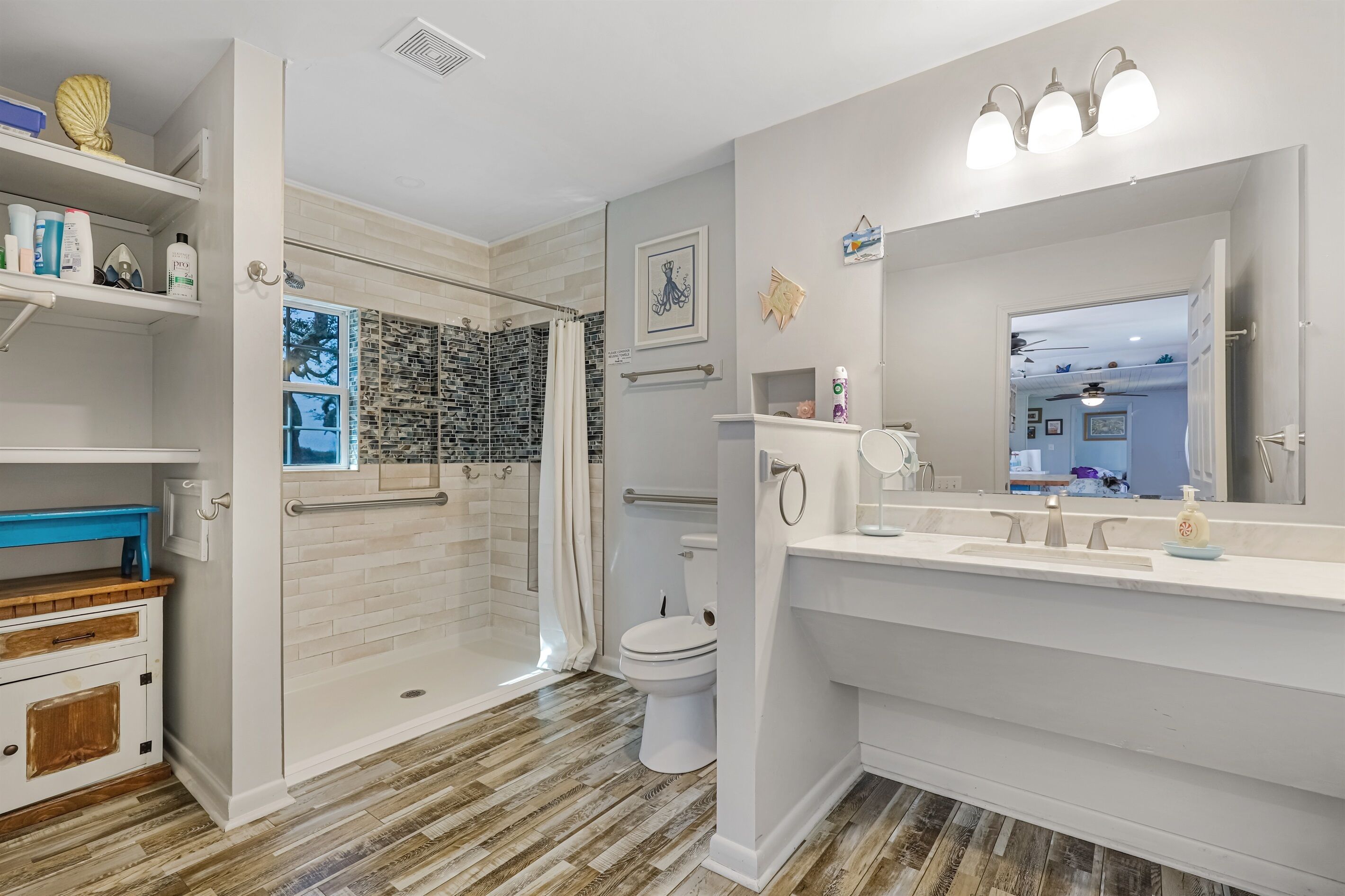 A modern bathroom with a walk-in shower, a toilet, and a vanity with a large mirror.