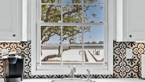A kitchen with a window, a sink, and a coffee maker. - Dolphin Cove • Dazzling Waterfront Cottage w/ Dock (Ocean Isle Beach)