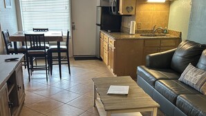 A living room with a leather sofa, a coffee table, and a dining area with a table and chairs. - On the beach (Daytona Beach)